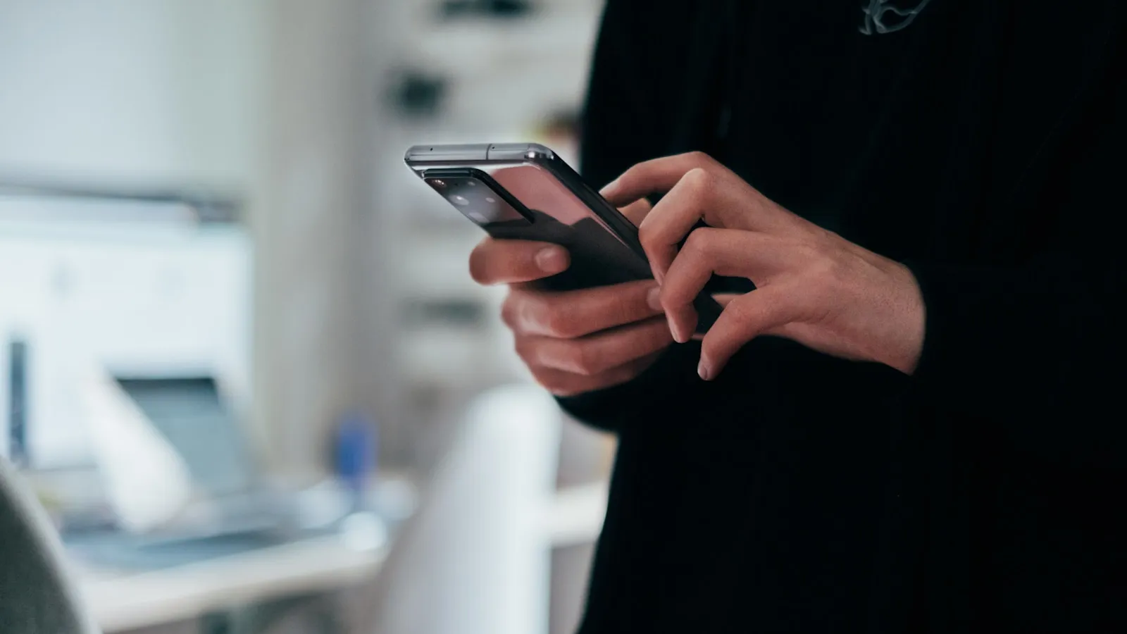 Persoană ținând un telefon și citind atentă un mesaj primit
