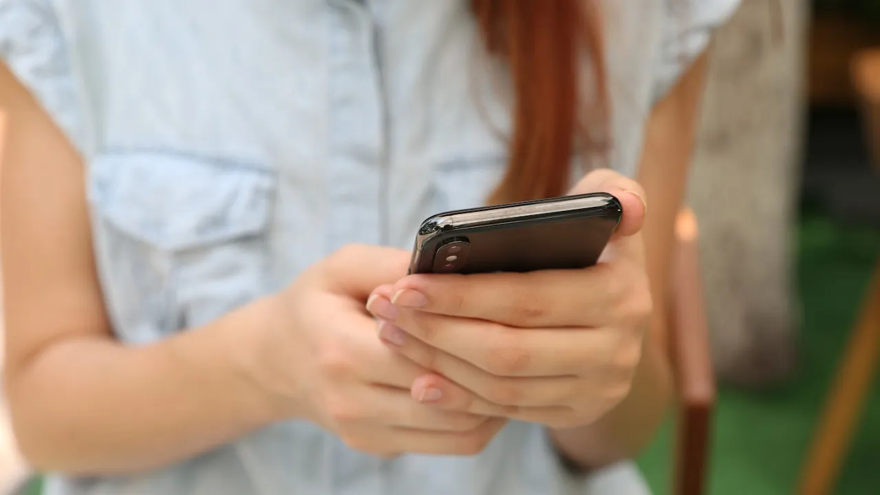 Mâini tinere ținând un telefon, într-un context de social media