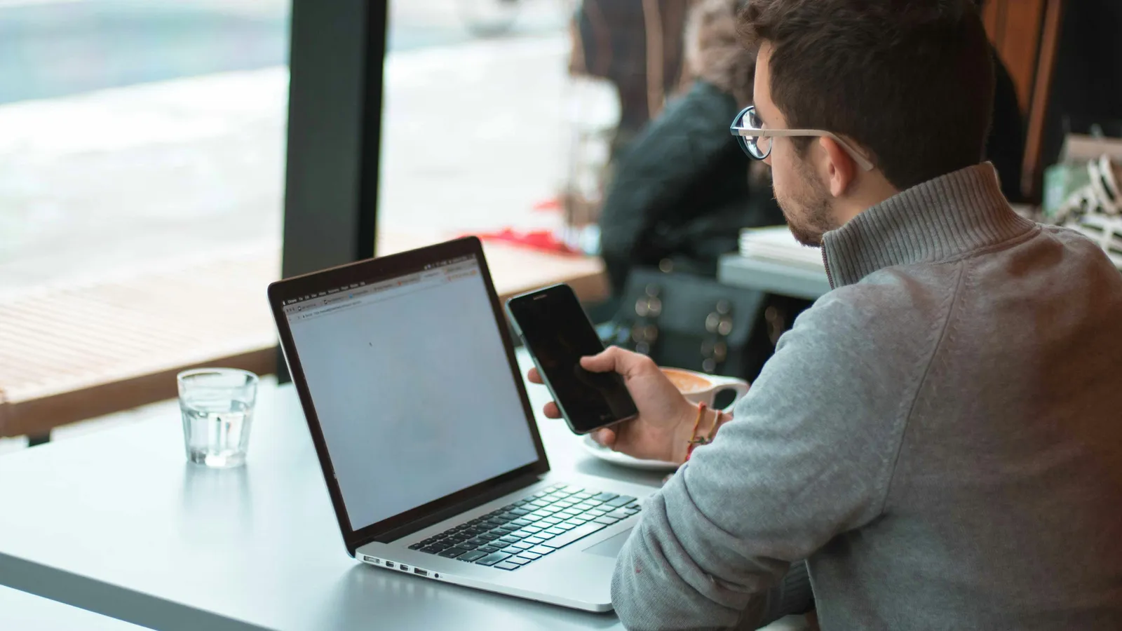 Persoană verificând o factură pe hârtie lângă un laptop, la birou
