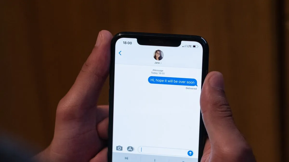 Prim-plan cu un telefon care afișează un SMS de la un presupus curier, cu un link de apăsat