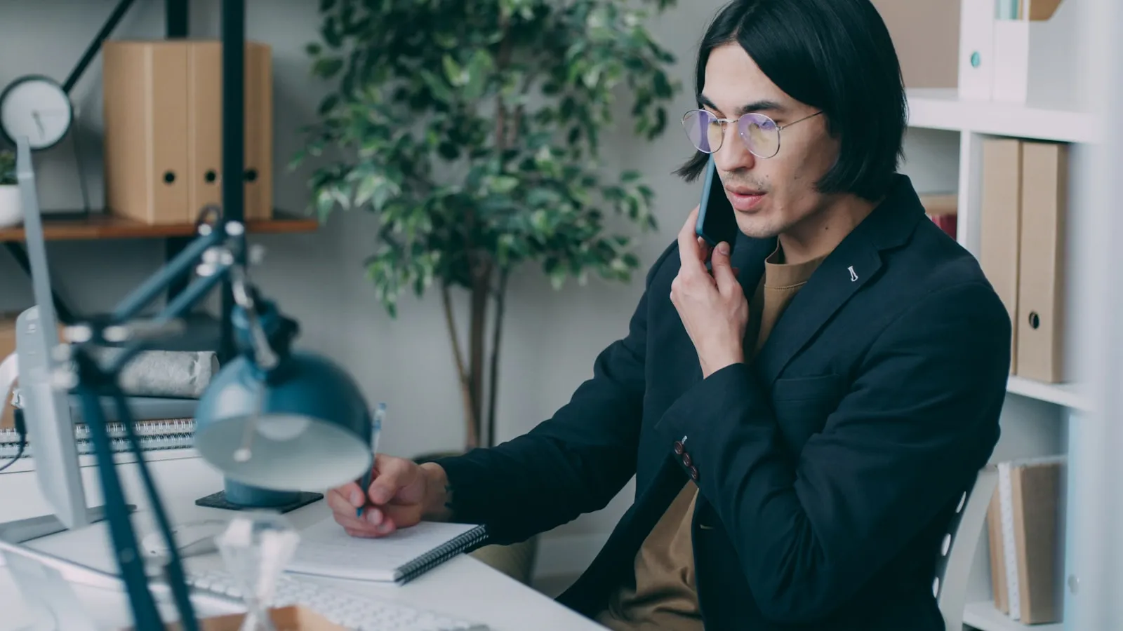 Profesionist la birou vorbind la telefon și notând informații în timp ce raportează o problemă
