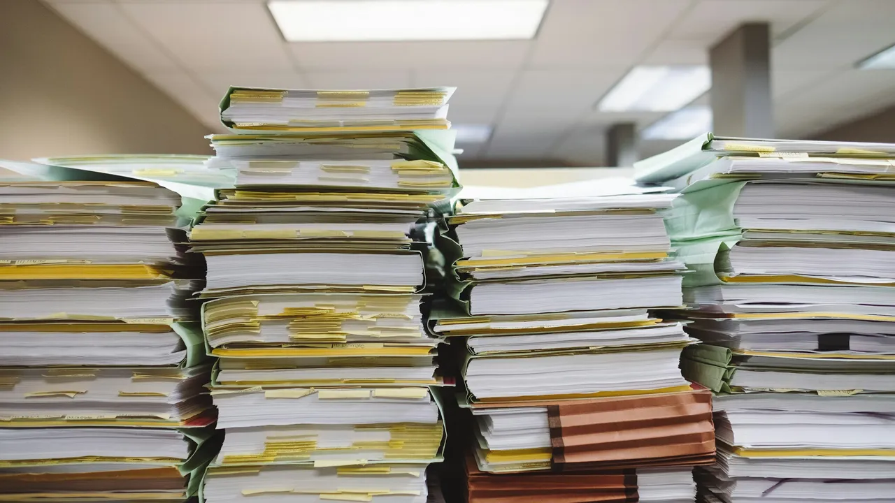 Teancuri de dosare și documente financiare stivuite într-un birou