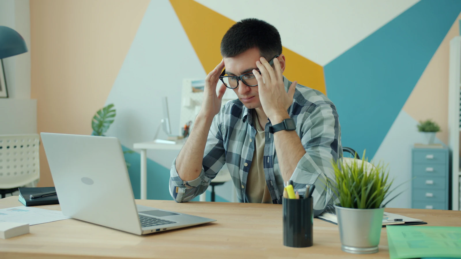 Antreprenor îngrijorat ținându-se de cap în fața laptopului