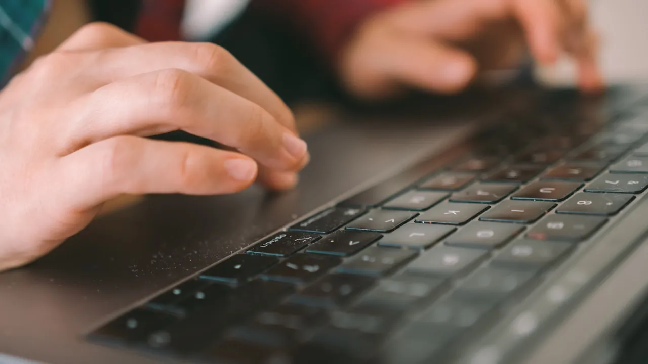 Mâini care lucrează pe tastatura unui laptop în timpul curățării unui site web