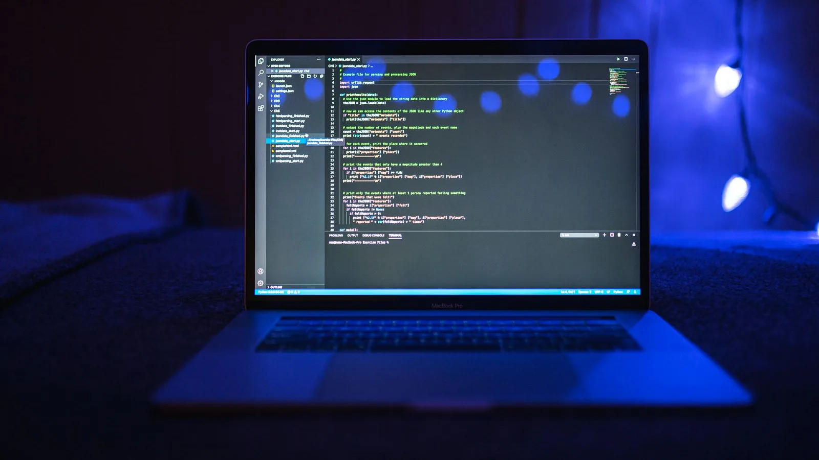 Laptop deschis, cu cod afișat pe ecran, într-o cameră întunecată